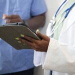 Black healthcare professionals reviewing information on a tablet in a clinical setting.