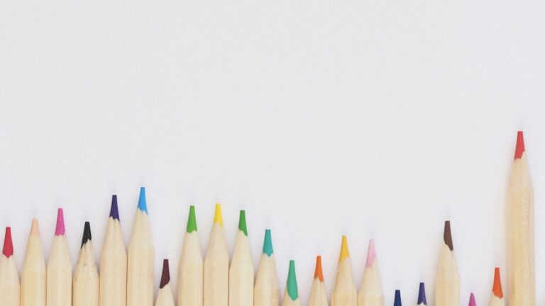 Coloured pencils arranged on a white surface, illustrating early childhood learning