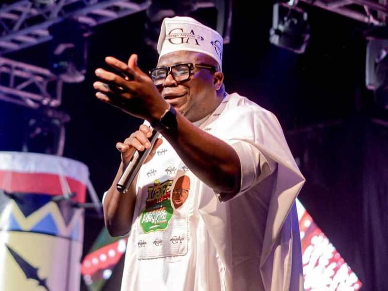 Gbenga Adeyinka performing on stage with a microphone during a Laffmattazz comedy show.