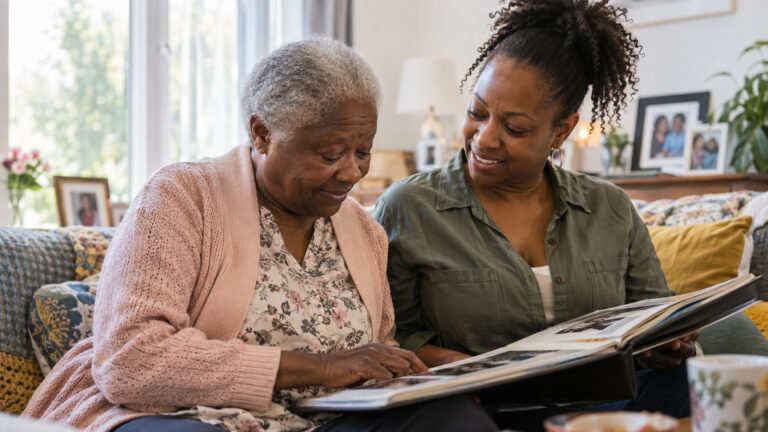 Older woman and adult daughter looking through a family photo album together