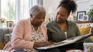 Older woman and her adult daughter looking through a family photo album at home