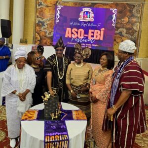 Guests in traditional attire gathered around a cake at Aso-Ebi Festival 2025