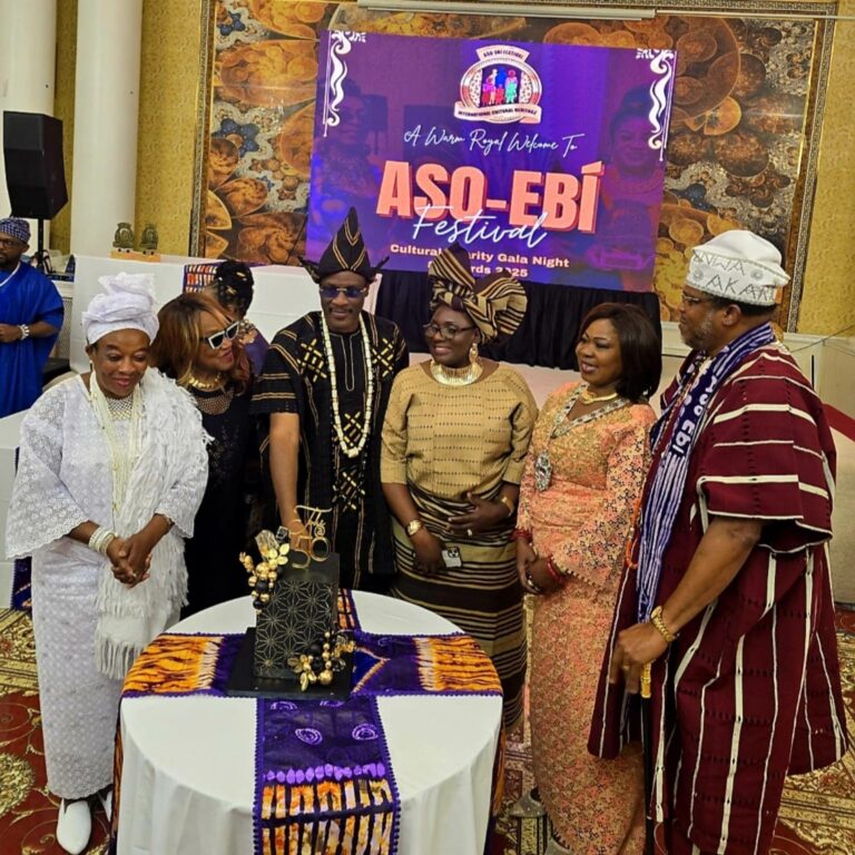 Guests in traditional attire gathered around a cake at Aso-Ebi Festival 2025