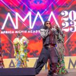 An Africa Movie Academy Awards winner holding the AMAA statuette on stage