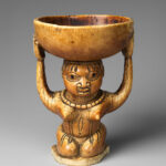 Ivory àgéré Ifá from Owo showing a kneeling woman supporting a bowl, dated to the seventeenth to nineteenth century.