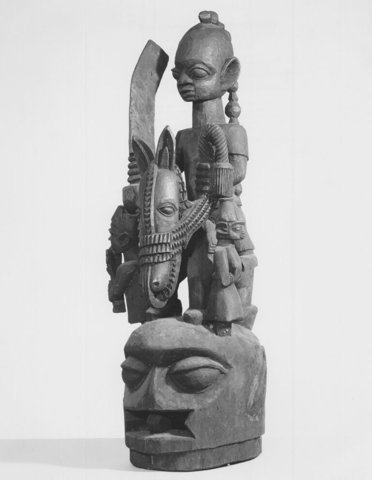 Black-and-white archive photograph of a Yoruba Ẹpa headdress with a mounted figure and attendants, Brooklyn Museum 70.107.13.