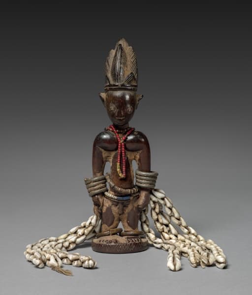 Yoruba-style ere ibeji memorial figure with beads, metal arm ornaments and cowrie shells, Cleveland Museum of Art, 2016.9.