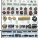 Glass beads of varying colours and shapes from Ile-Ife, including cylindrical and perforated beads.