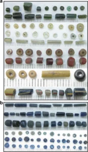 Glass beads of varying colours and shapes from Ile-Ife, including cylindrical and perforated beads.