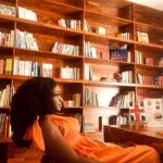 Ibi Kontein, Sabi Arts founder and creative director, seated beside bookshelves in the company’s official team photograph.