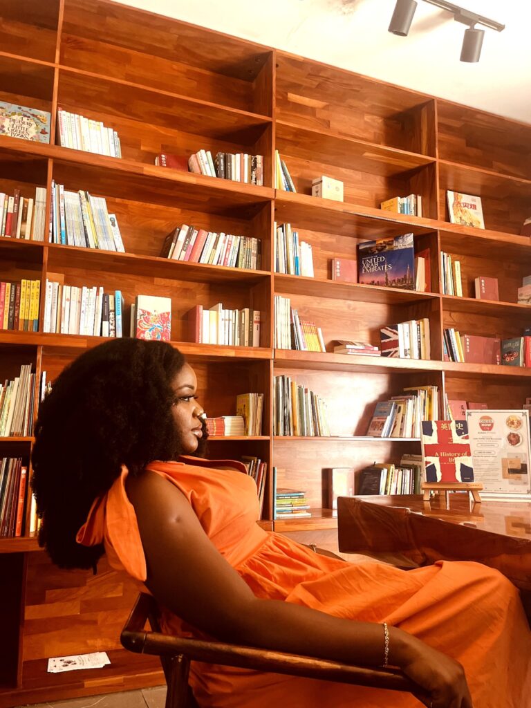 Ibi Kontein, Sabi Arts founder and creative director, seated beside bookshelves in the company’s official team photograph.