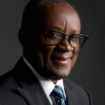 John Enoh in a suit and glasses, photographed on 17 August 2023. Archive portrait.