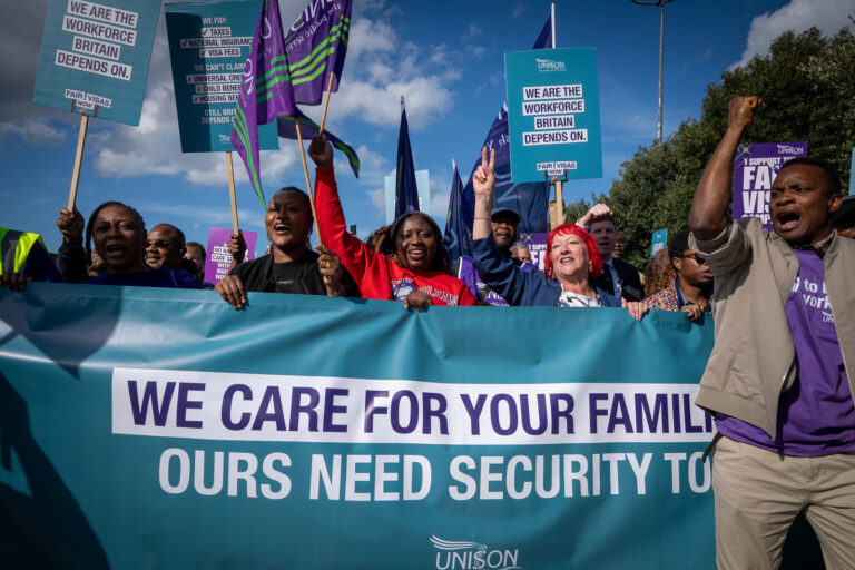 Migrant care workers holding We Care for Your Families banner at the Liverpool demonstration