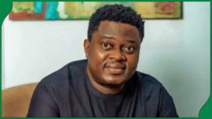 Nollywood actor Muyiwa Ademola wearing a dark shirt in a seated portrait.