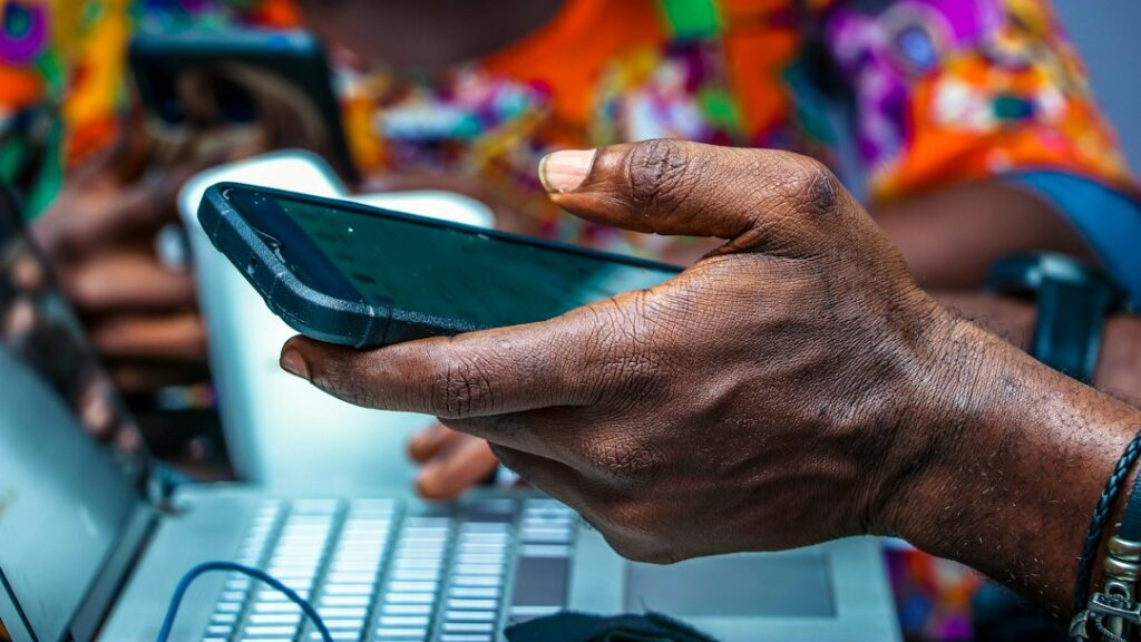 Nigerian man using a smartphone, illustrating Lagos cybersecurity awareness and online fraud prevention