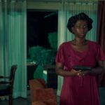 A woman in a burgundy dress holds a handgun in an interior scene from Phoenix Fury