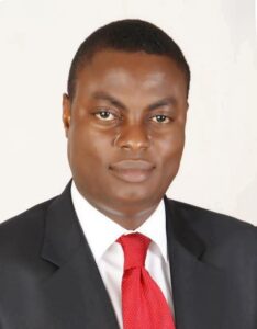 Pius Osunyikanmi wearing a dark suit, white shirt and red tie.