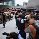 Group of press photographers holding cameras at a public event