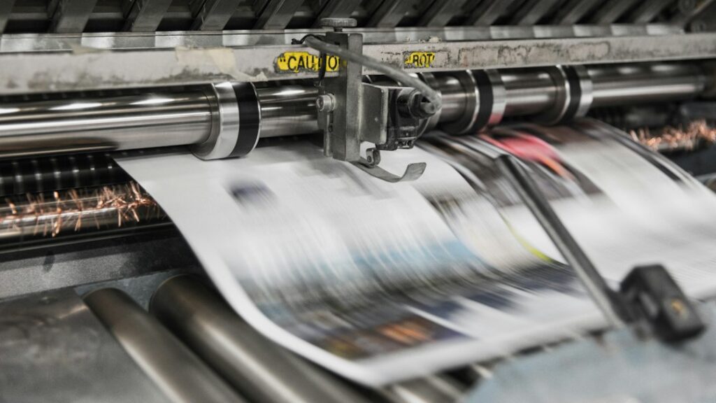 Printed pages moving through a press, illustrating the publishing industry