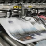Printed pages moving through a press, illustrating the publishing industry