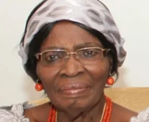 Professor Kamene Okonjo wearing glasses, a patterned headwrap and coral jewellery.