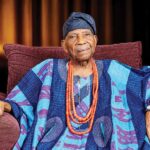 Reuben Fasoranti seated in traditional Yoruba attire and a blue cap