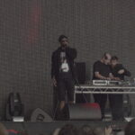 Skepta holding a microphone on stage at Field Day in London on 11 June 2016